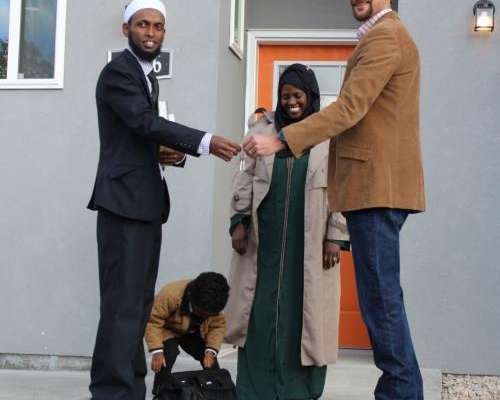 Man handing a set of house keys to a family. 