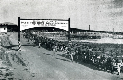 Image of soldiers marching through a gate to an airforce base. 