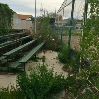 Image of dilapidated seating behind a ball field.